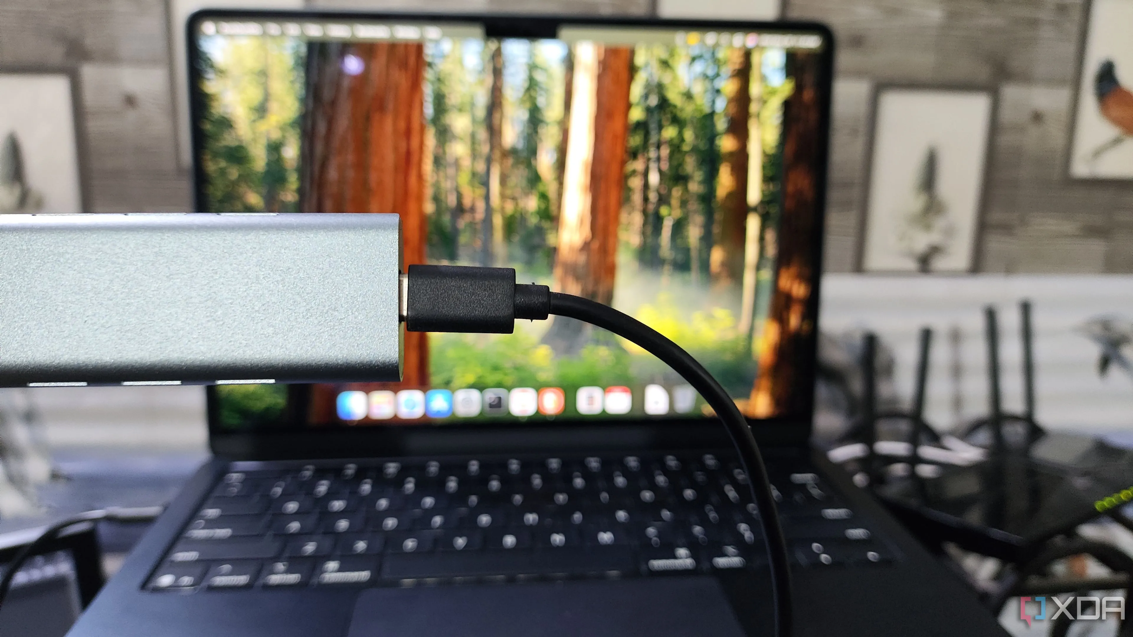 Cầm vỏ bảo vệ ổ NVMe SSD trước máy tính MacBook, minh họa cách biến ổ NVMe cũ thành ổ di động siêu tốc