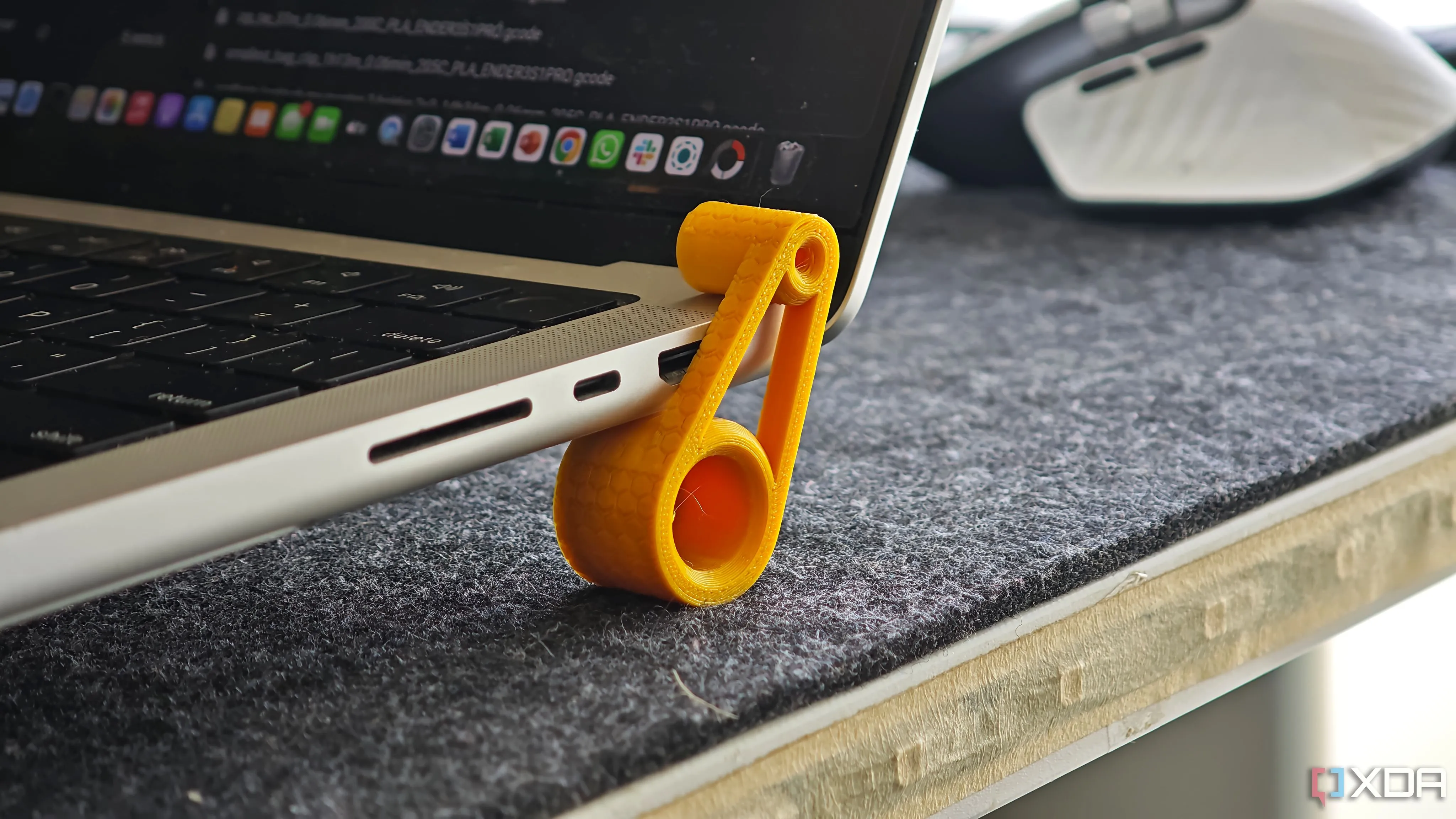 Chân kê công thái học in 3D màu đen đặt dưới laptop, nâng nhẹ phần sau bàn phím