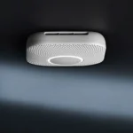 Đầu báo khói thông minh Google Nest với nút bấm tròn chính giữa và logo Google