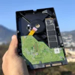 Hình ảnh một người đang cầm ổ cứng HDD và SSD để vệ sinh NAS.