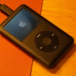 iPod Classic màu trắng với bánh xe điều khiển click wheel và logo Apple, biểu tượng của kỷ nguyên máy nghe nhạc di động.