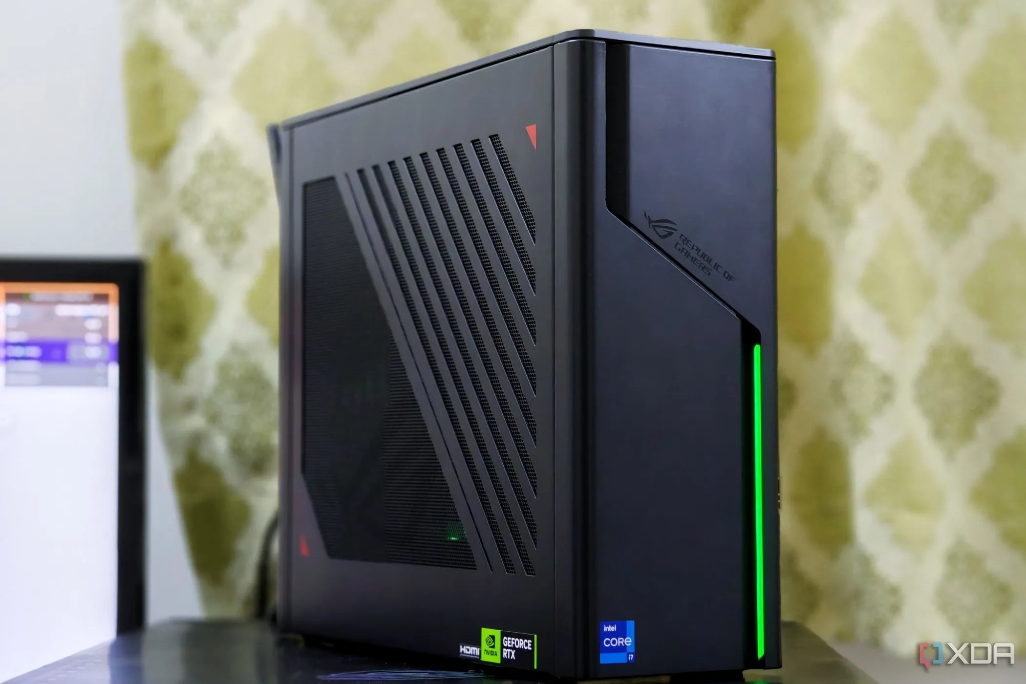 Máy tính PC SFF ASUS ROG G22CH đặt gọn gàng trên bàn làm việc cạnh màn hình, thể hiện tính di động