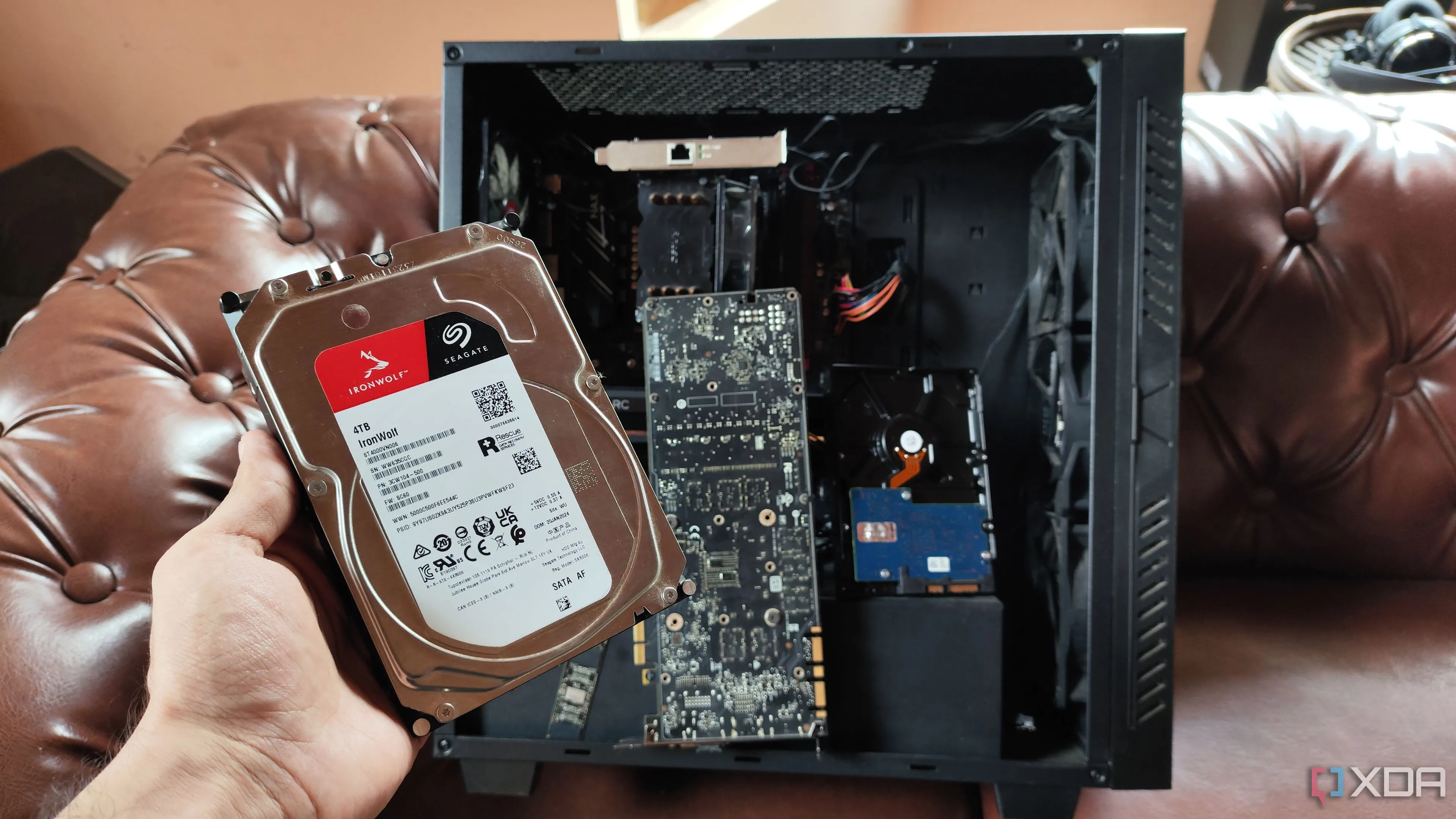 Một người đang cầm ổ cứng HDD trước hệ thống NAS tự lắp đặt