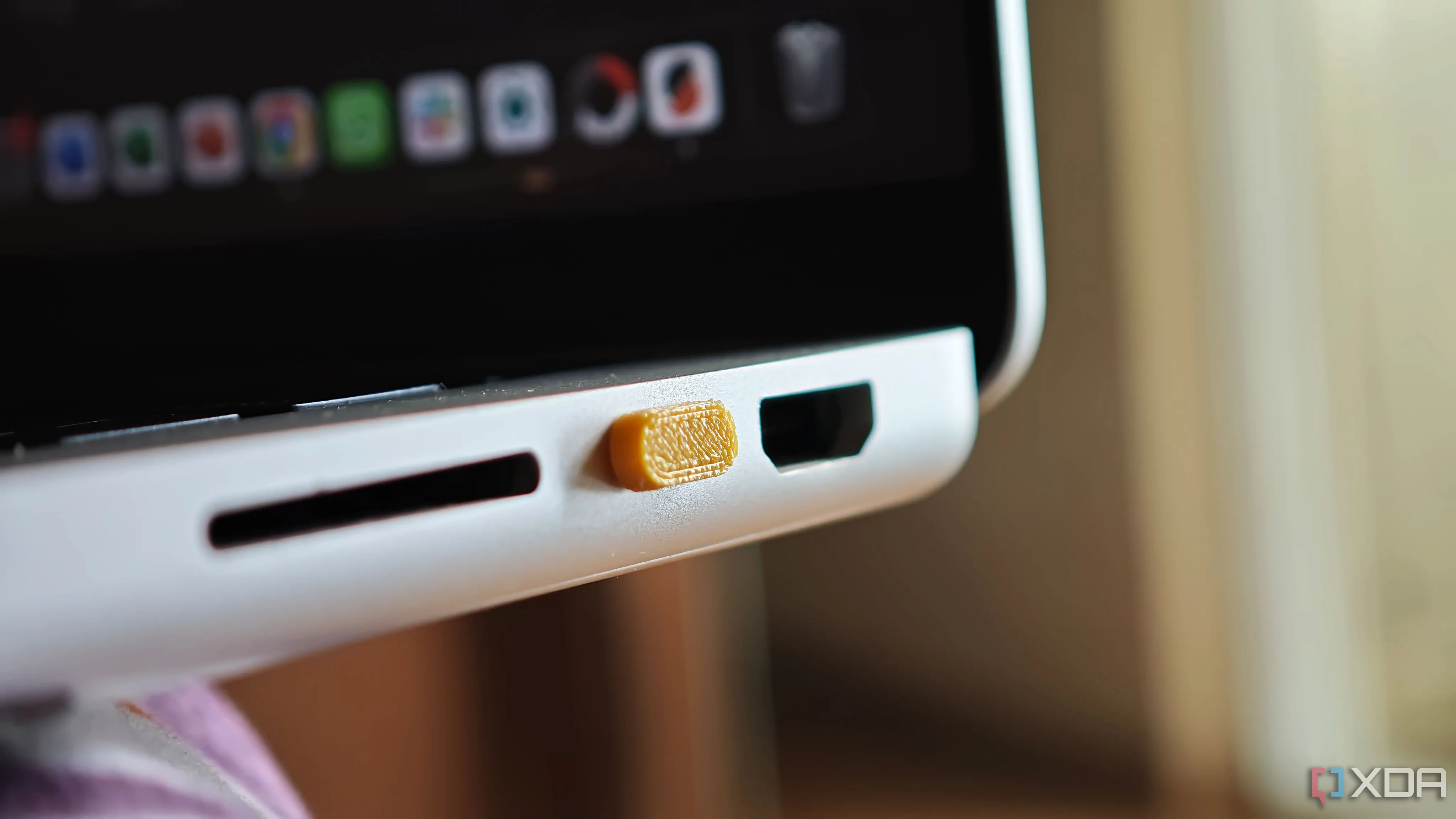 Nắp đậy cổng USB-C màu đen in 3D được gắn vào cổng của laptop MacBook