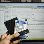 Người dùng cầm ổ cứng SSD, HDD nội bộ và HDD ngoài trước màn hình Proxmox, minh họa sự đa dạng các giải pháp lưu trữ dữ liệu bền vững.