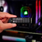 Người dùng cầm ổ cứng SSD WD Black SN850X Gaming cùng dàn máy tính PC chơi game có đèn RGB phía sau