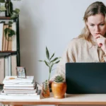 Người phụ nữ nhìn màn hình laptop đầy lo lắng trước cảnh báo virus hoặc lỗi phần mềm.
