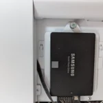 Ổ cứng SSD Samsung 860 EVO 250GB màu đen được lắp đặt trên vỏ máy tính màu trắng, minh họa cho việc tiết kiệm điện năng của SATA SSD.