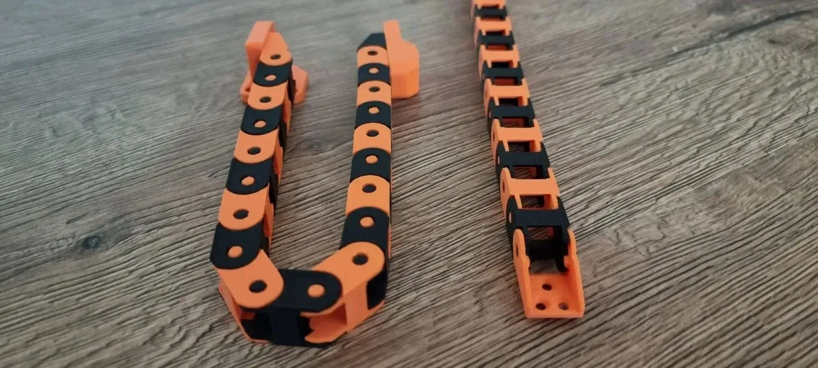 Xích cáp linh hoạt (drag chain) được in 3D với các đoạn nối có khớp, bảo vệ và định tuyến dây điện cho các thiết bị chuyển động như máy in 3D, giúp tăng tính thẩm mỹ và độ bền.
